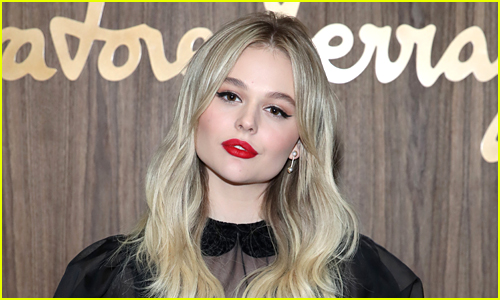 Emily Alyn Lind wears a red lip while posing in front of a brown backdrop