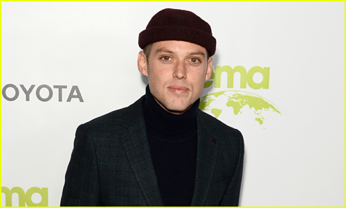 Harry Hudson wears all black while posing in front of a white backdrop