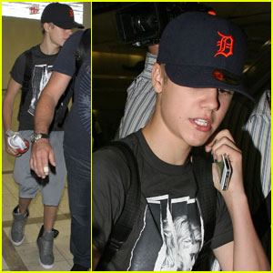 Justin Bieber dons a hoodie and baseball cap with skinny jeans at LAX