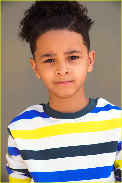 Sebastian Cote poses in front of a gray background in a striped shirt