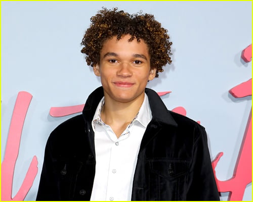 Armani Jackson wears a white button up and blue jacket at a premiere event