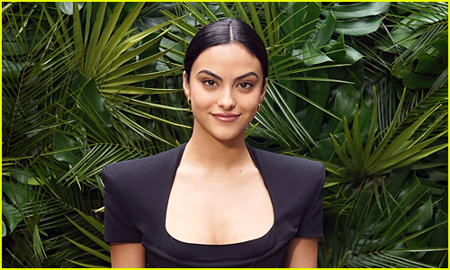 Camila Mendes wearing black in front of a foliage background