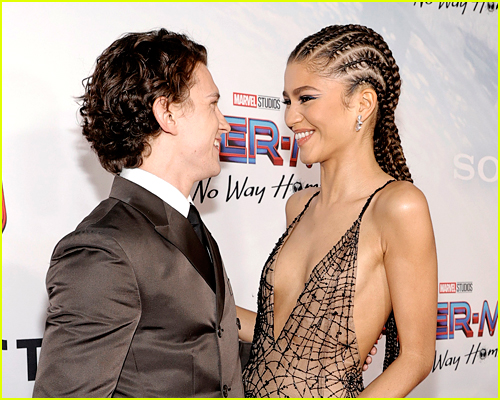 Tom Holland and Zendaya looking at each other smiling on a red carpet